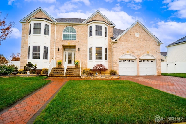 traditional-style house with brick siding, decorative driveway, and a garage