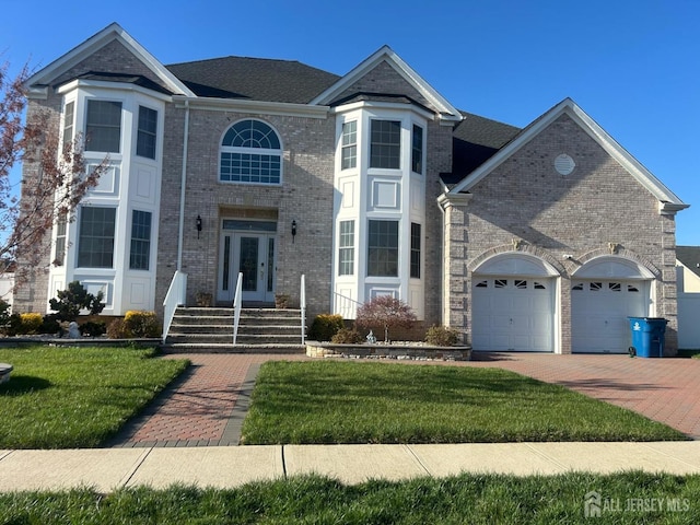 view of front of home featuring brick siding, a front lawn, decorative driveway, and a garage