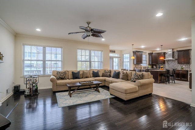 living area with wood-type flooring, a ceiling fan, ornamental molding, recessed lighting, and baseboards
