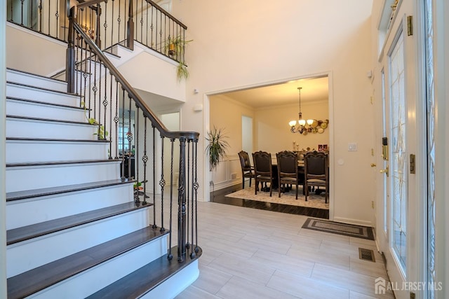 foyer entrance featuring a high ceiling, stairs, a chandelier, and ornamental molding