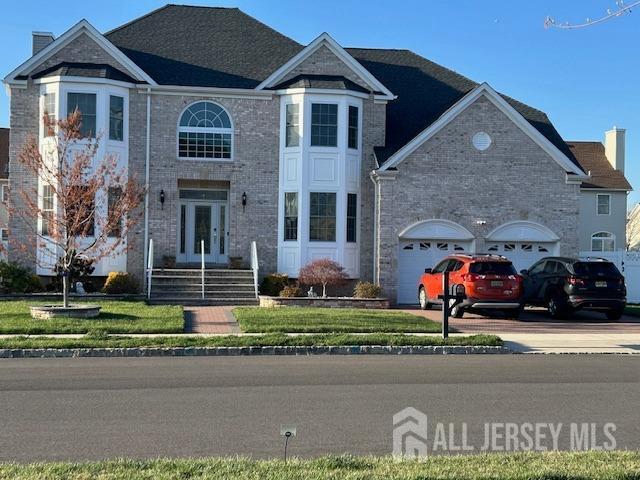 traditional-style house featuring brick siding, a garage, concrete driveway, and french doors