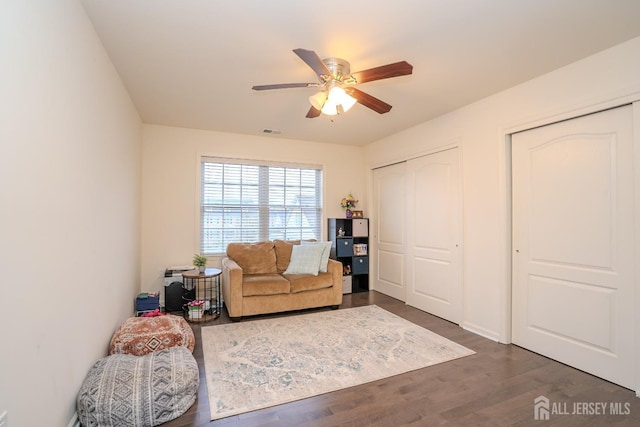 sitting room with ceiling fan and dark wood finished floors