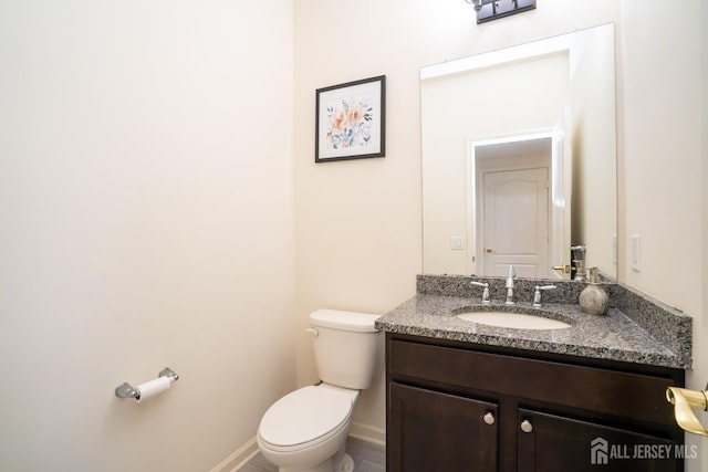 half bathroom with toilet, vanity, and baseboards