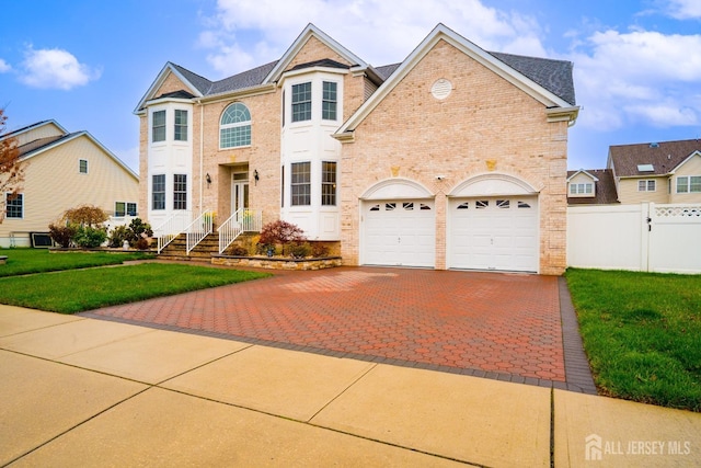 traditional-style house with decorative driveway, brick siding, and a garage