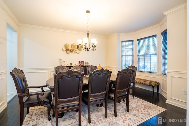 dining space with a chandelier, a decorative wall, wood finished floors, ornamental molding, and a wainscoted wall