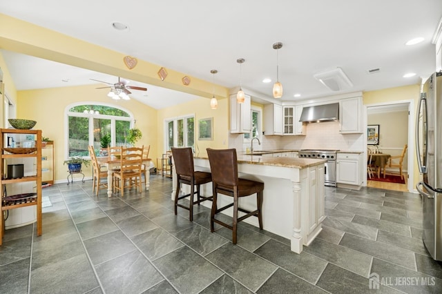 2 Derby Ln, East Brunswick, NJ 08816 - kitchen with stainless steel appliances, wall chimney exhaust hood, a breakfast bar, a ceiling fan, and white cabinets
