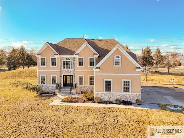 view of front of home featuring stone siding, a front lawn, and stucco siding