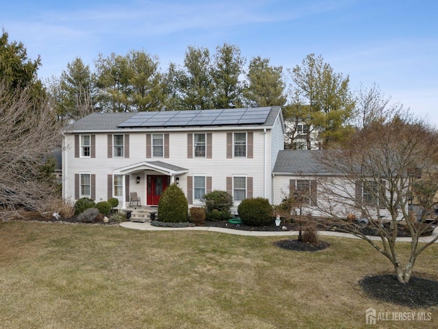 colonial-style house featuring solar panels and a front yard