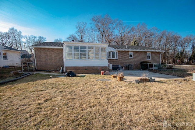 rear view of house featuring a lawn, a patio, fence, cooling unit, and brick siding