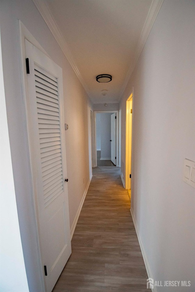 hall with baseboards, wood finished floors, and crown molding