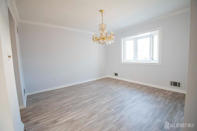 unfurnished room with wood finished floors, visible vents, baseboards, and ornamental molding