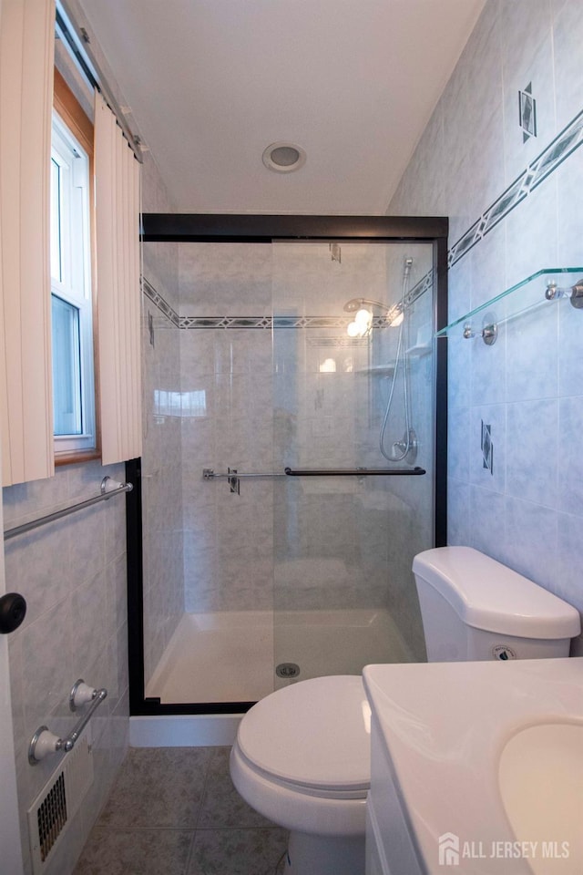 full bathroom featuring tile patterned flooring, toilet, a stall shower, and tile walls