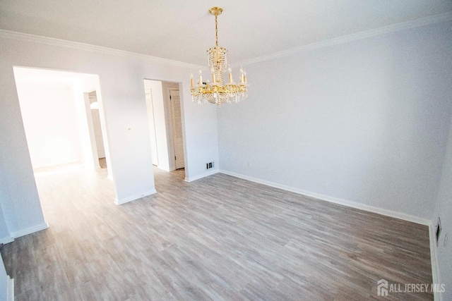 empty room featuring visible vents, baseboards, wood finished floors, and ornamental molding