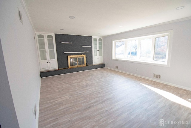 unfurnished living room featuring visible vents, a large fireplace, baseboards, and wood finished floors