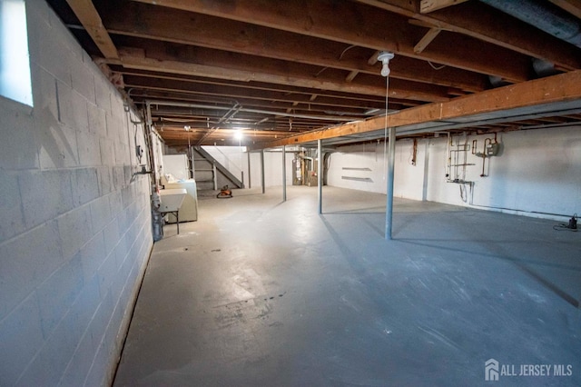 unfinished below grade area featuring gas water heater and stairs