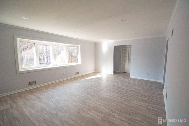 unfurnished room with visible vents, crown molding, baseboards, and wood finished floors