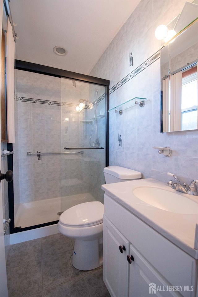 bathroom with toilet, a stall shower, tile walls, tile patterned flooring, and vanity