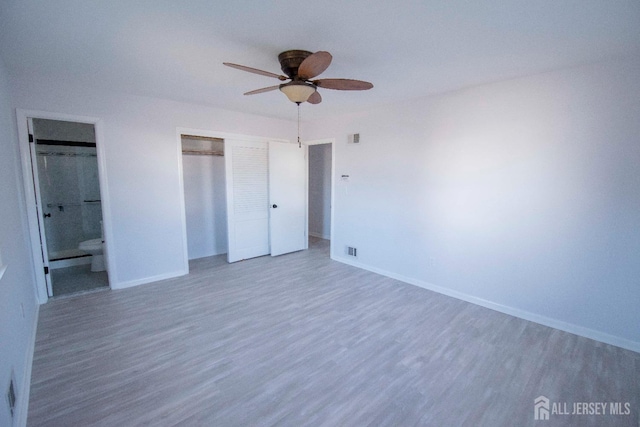 unfurnished bedroom with visible vents, wood finished floors, connected bathroom, a closet, and baseboards