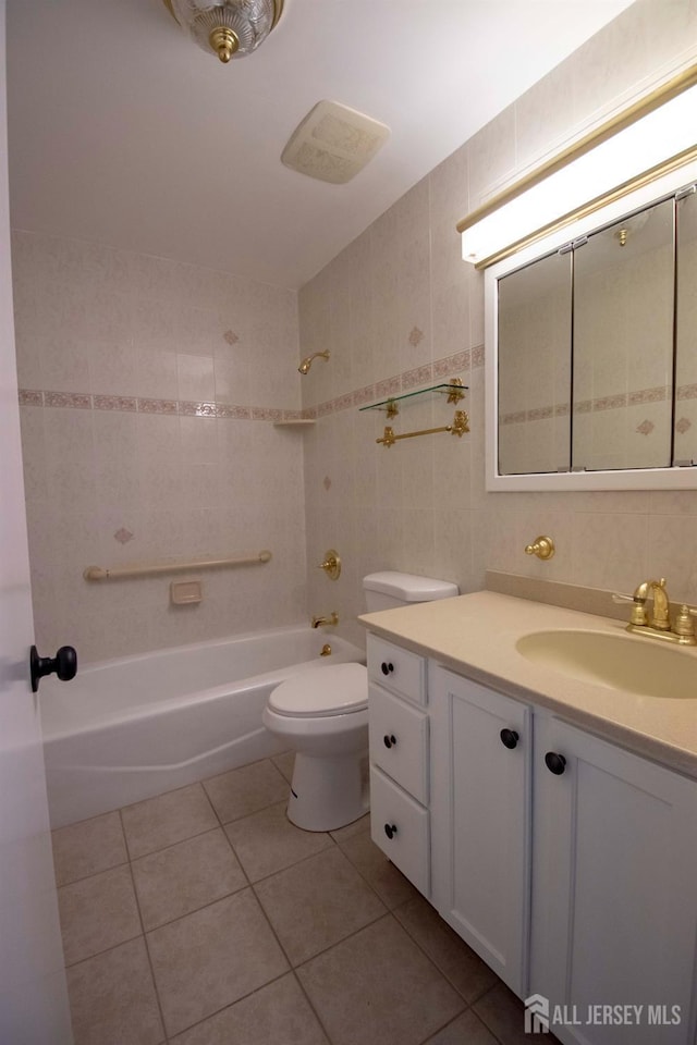 bathroom featuring shower / washtub combination, toilet, vanity, tile patterned floors, and tile walls