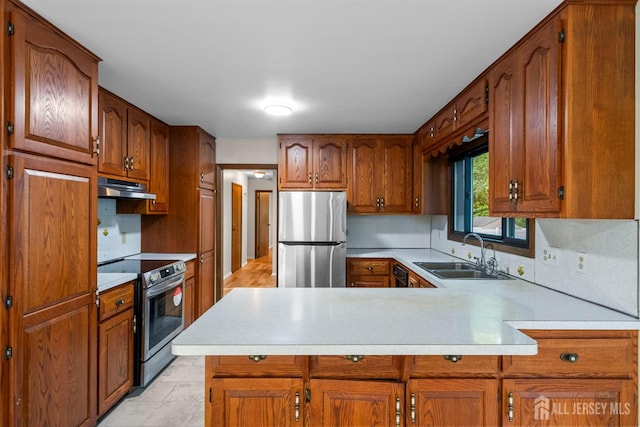 39 Miara St, Sayreville, NJ 08859 - kitchen with stainless steel appliances, under cabinet range hood, light countertops, a peninsula, and brown cabinetry