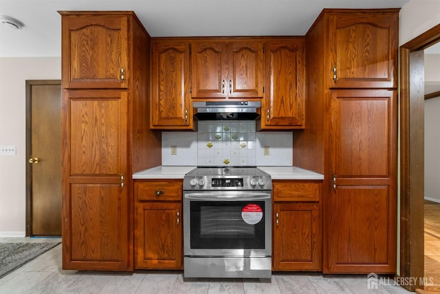39 Miara St, Sayreville, NJ 08859 - kitchen featuring stainless steel range with electric stovetop, under cabinet range hood, light countertops, backsplash, and brown cabinetry