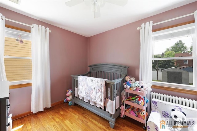 49 Paul St, Fords, NJ 08863 - bedroom with wood finished floors, radiator, ceiling fan, and a crib