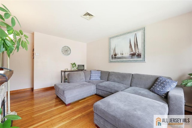 49 Paul St, Fords, NJ 08863 - living room with light wood-style floors and a baseboard heating unit