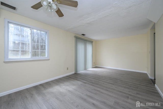 spare room featuring baseboards, a ceiling fan, wood finished floors, and visible vents