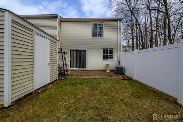 rear view of property featuring a yard, fence, an outbuilding, and cooling unit
