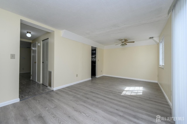 unfurnished room featuring baseboards, ceiling fan, wood finished floors, and visible vents