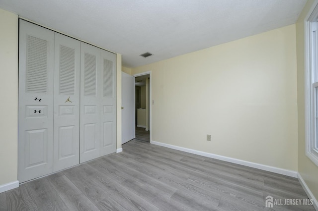 unfurnished bedroom featuring baseboards, visible vents, and wood finished floors