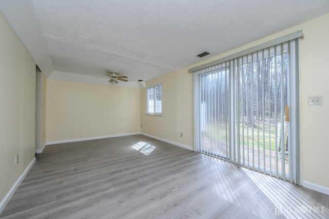unfurnished room featuring visible vents, wood finished floors, baseboards, ceiling fan, and a textured ceiling