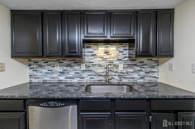 kitchen featuring stainless steel dishwasher, dark cabinets, a sink, and tasteful backsplash