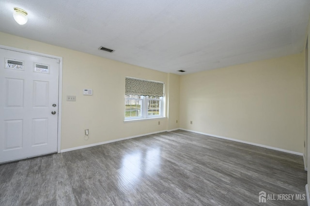 spare room with baseboards, visible vents, and wood finished floors