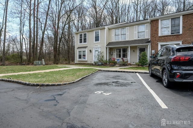 view of front facade with uncovered parking and a front lawn