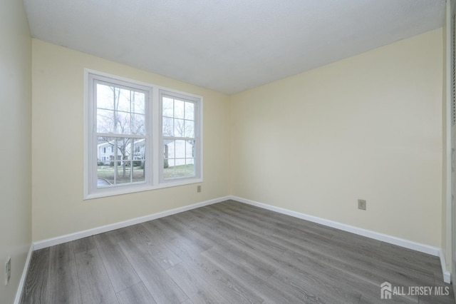 spare room featuring baseboards and dark wood finished floors