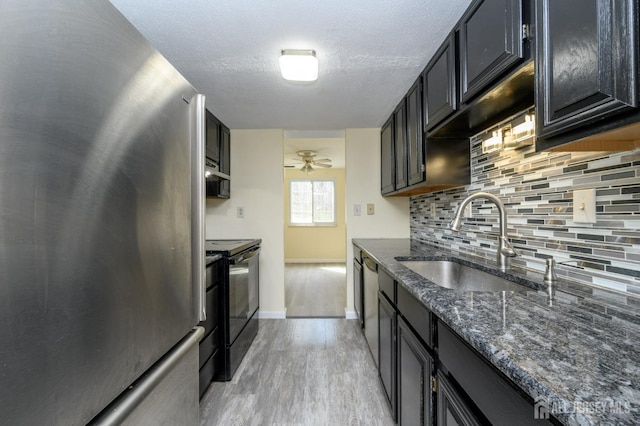 kitchen featuring black / electric stove, backsplash, light wood-type flooring, a sink, and freestanding refrigerator