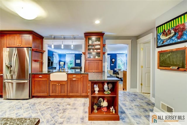 kitchen with decorative backsplash, dark stone countertops, stainless steel fridge with ice dispenser, and sink