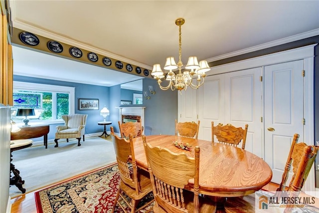 carpeted dining area with a fireplace, an inviting chandelier, and ornamental molding