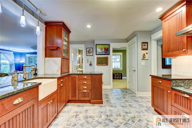 kitchen featuring sink, hanging light fixtures, backsplash, kitchen peninsula, and dark stone counters