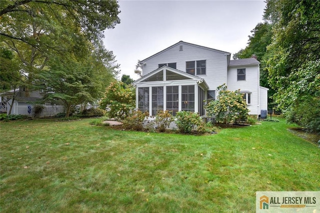 back of property with a sunroom and a yard