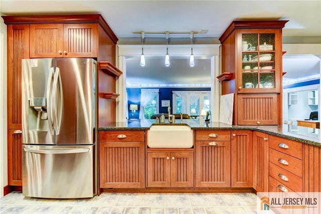 kitchen with decorative light fixtures, dark stone countertops, stainless steel fridge with ice dispenser, and sink