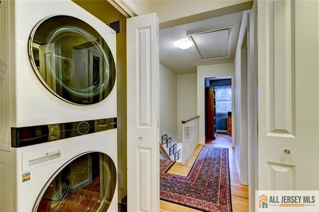 clothes washing area featuring light wood-type flooring and stacked washer and dryer