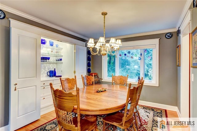 dining area featuring light wood-type flooring, crown molding, and a chandelier