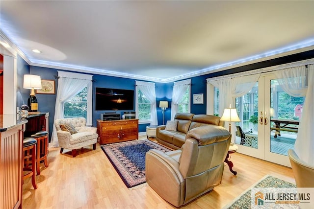 living room featuring french doors, ornamental molding, and light wood-type flooring