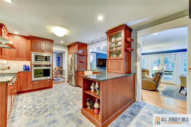 kitchen featuring dark stone counters, light wood-type flooring, tasteful backsplash, kitchen peninsula, and stainless steel appliances