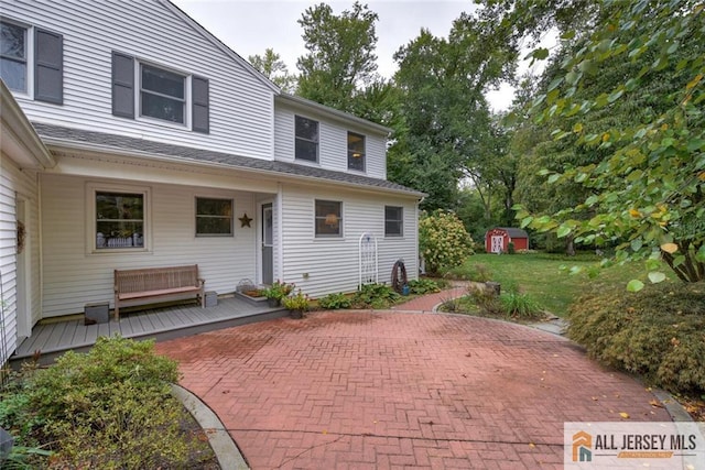 view of patio featuring a wooden deck and a storage shed