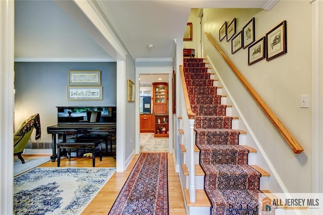 stairs featuring wood-type flooring and ornamental molding