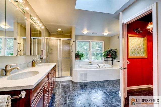 bathroom featuring a skylight, vanity, and independent shower and bath