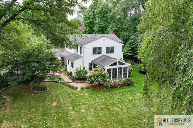 back of house featuring a lawn and a sunroom